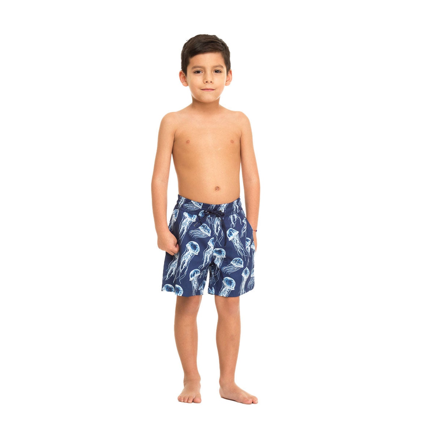Young boy wearing navy blue swim shorts with white patterns on a white background