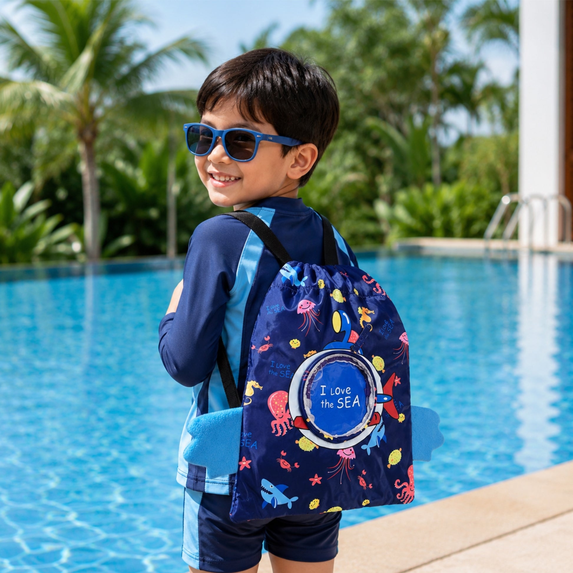 Child with a 'I love the Sea' swimming backpack by a pool