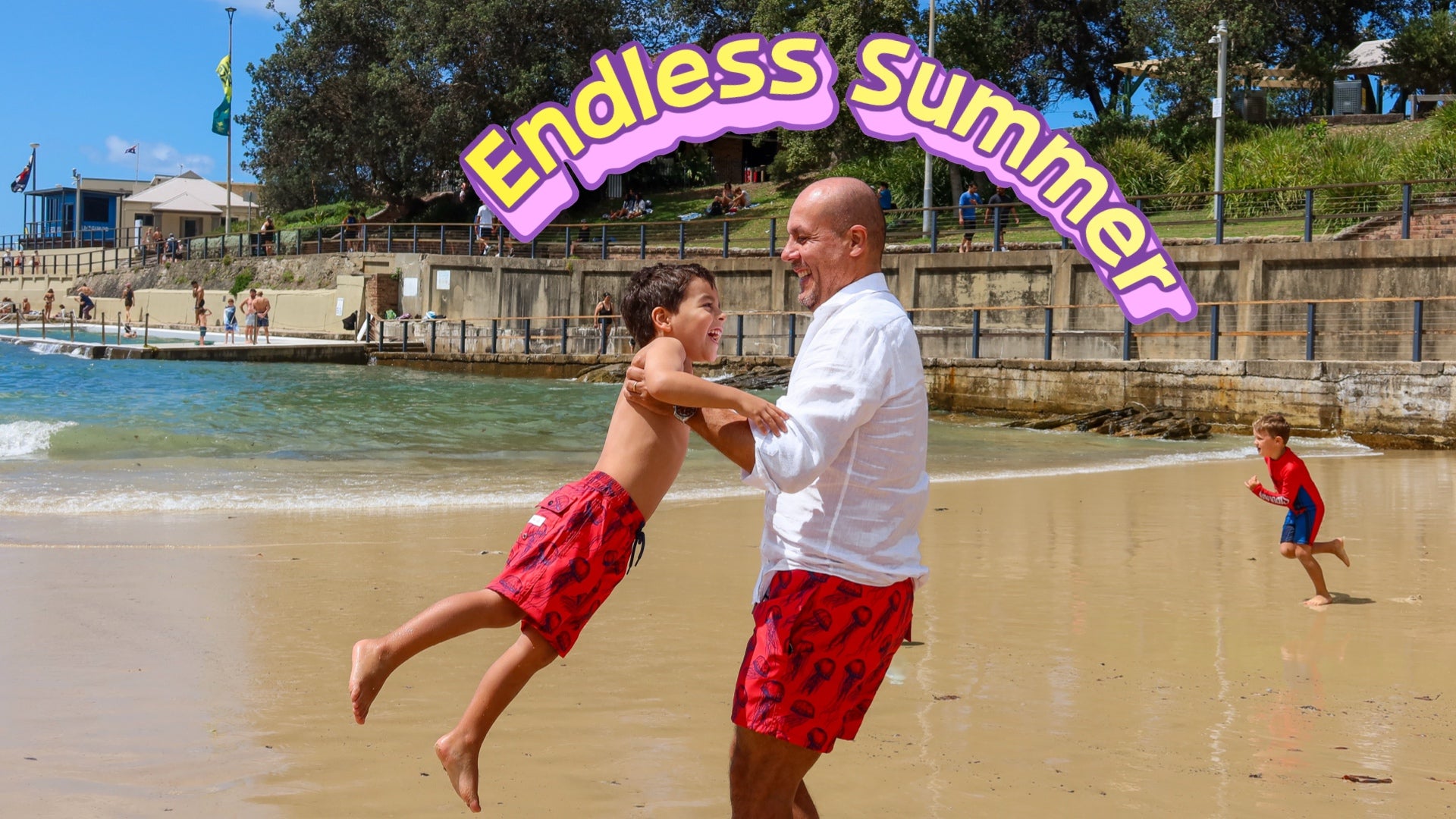 father and son playing on a beach with matching dad and son swimwear