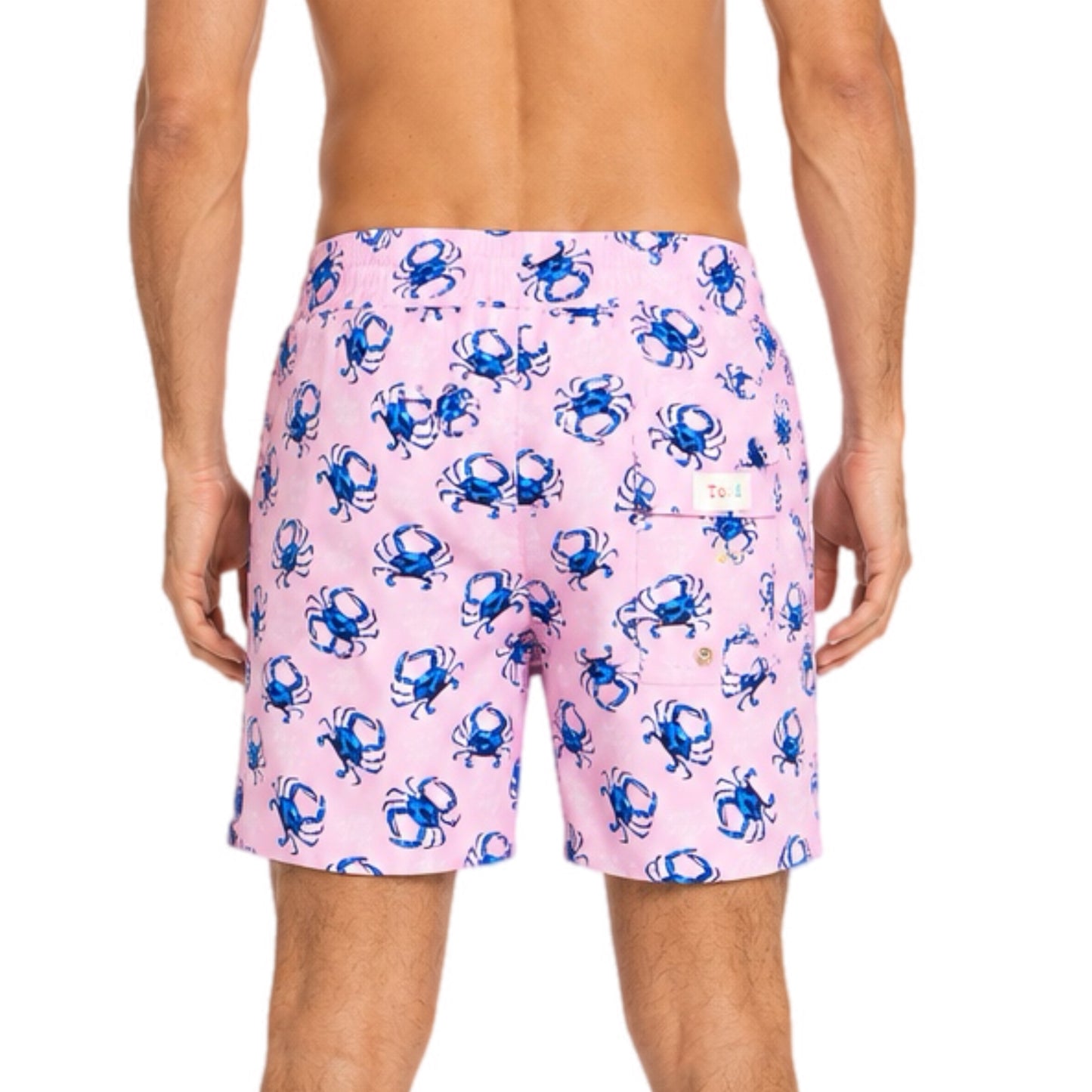 Pink swim shorts with blue crab pattern worn by a person on a white background