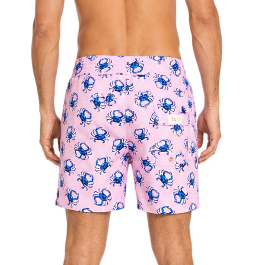 Pink swim shorts with blue crab pattern worn by a person on a white background