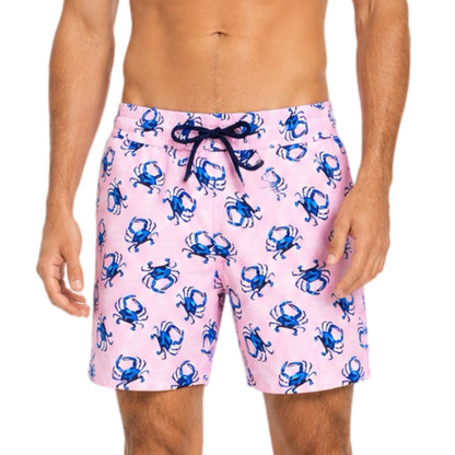Pink swim shorts with blue crab pattern worn by a person on a white background