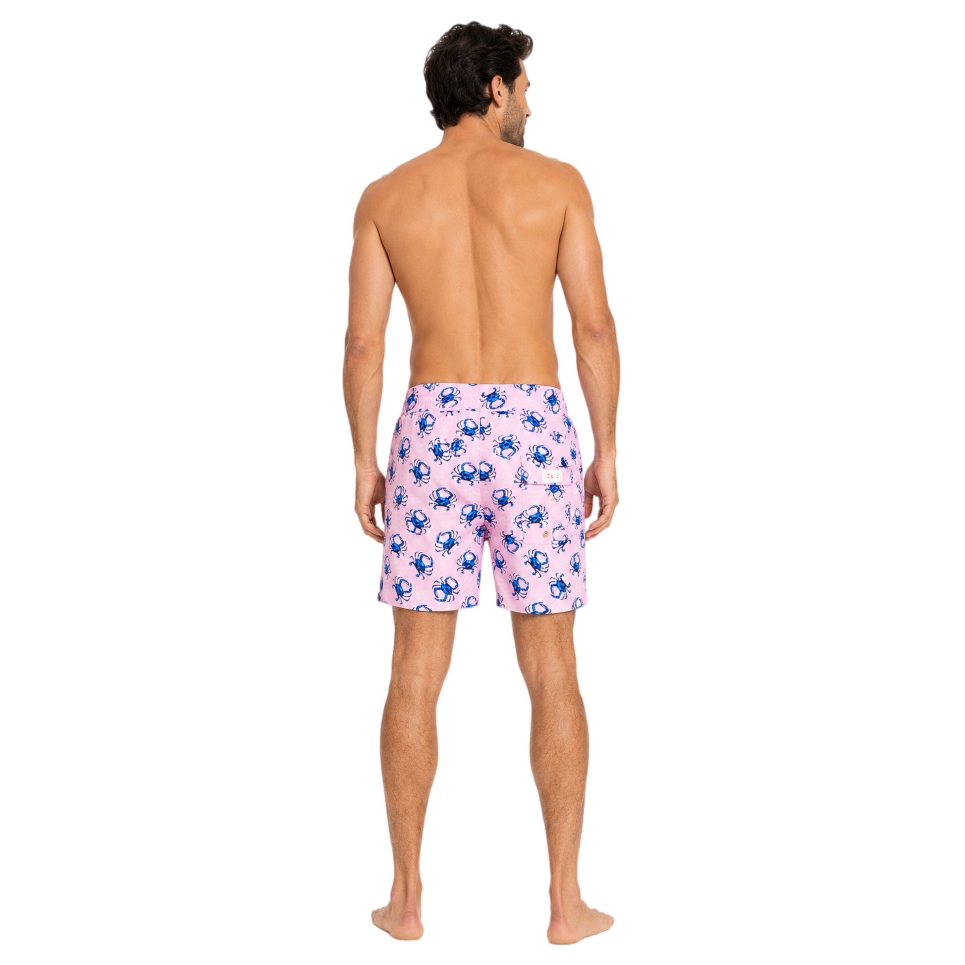Man wearing pink swim shorts with blue crab pattern on a white background