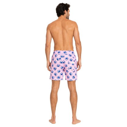 Man wearing pink swim shorts with blue crab pattern on a white background